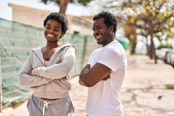African american man and woman sporty couple standing with arms crossed gesture at street