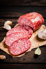 Pieces of salami sausage with garlic and bay leaf on paper. 
