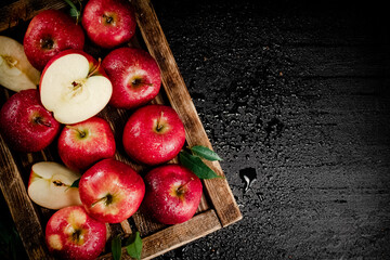 Pieces and whole red apples on a wooden tray. 