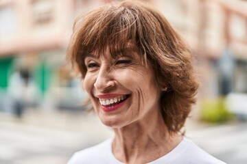 Middle age woman smiling confident looking to the side at street