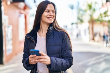 Fototapeta premium Young beautiful hispanic woman smiling confident using smartphone at street