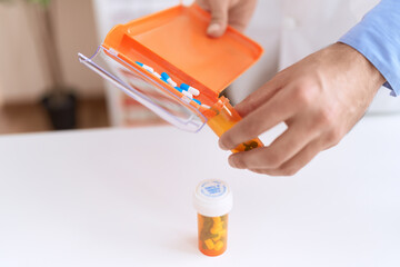 Young hispanic man pharmacist pouring pills on tube at pharmacy