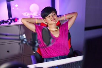 Middle age chinese woman streamer smiling confident relaxed with hands on head at gaming room