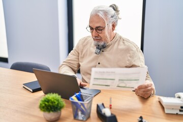 Middle age grey-haired man business worker using laptop reading document at office