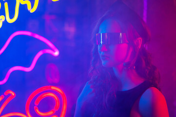 Caucasian woman in sunglasses posing in fog in neon studio.