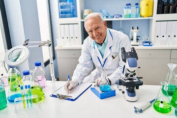 Senior man wearing scientist uniform measuring liquid at laboratory