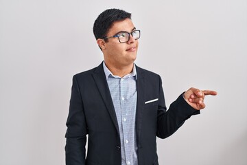 Young hispanic man with down syndrome wearing business style smiling with happy face looking and pointing to the side with thumb up.