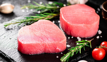 Raw tuna on a stone board with rosemary and garlic. 