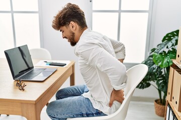Young arab man suffering for back pain working at office