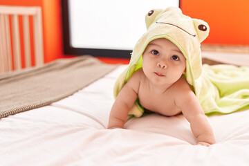 Adorable hispanic toddler wearing funny towel lying on bed at bedroom