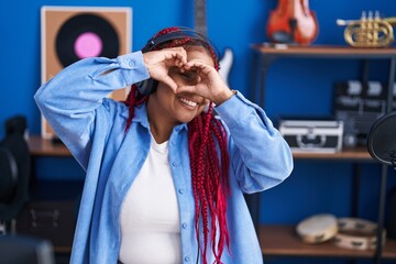 African american woman artist doing heart gesture with hands at music studio
