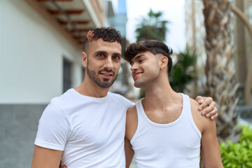 Fototapeta premium Two hispanic men couple smiling confident hugging each other at street