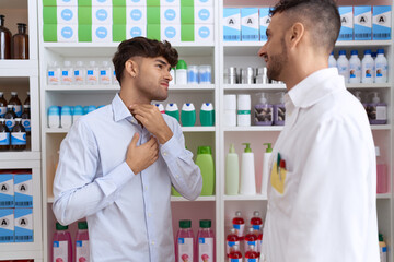 Two hispanic men pharmacist speaking to client suffering for throat pain at pharmacy