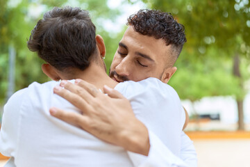 Two hispanic men couple smiling confident hugging each other at park