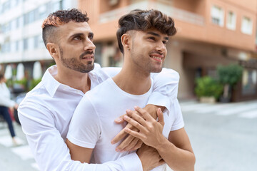 Two hispanic men couple smiling confident hugging each other at street