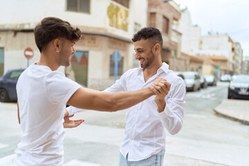 Two hispanic men couple smiling confident dancing at street