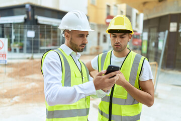 Two hispanic men architects using smartphone standing at street