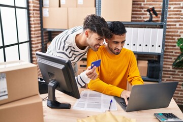 Two man ecommerce business workers using laptop and credit card at office