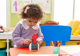 Adorable hispanic girl playing with toy standing at kindergarten