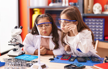Two kids students blowing to windmill turbine at kindergarten