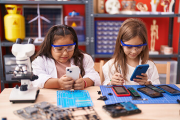 Fototapeta premium Two kids students using smartphones standing at laboratory classroom