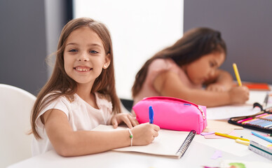 Two kids preschool students sitting on table drawing on paper at classroom