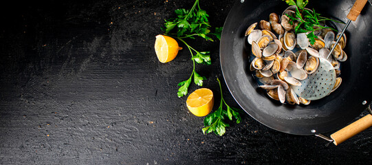 Vongole in a saucepan with lemon slices and parsley. 