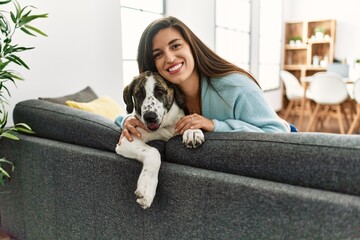 Young woman smiling confident sitting on sofa with dog at home