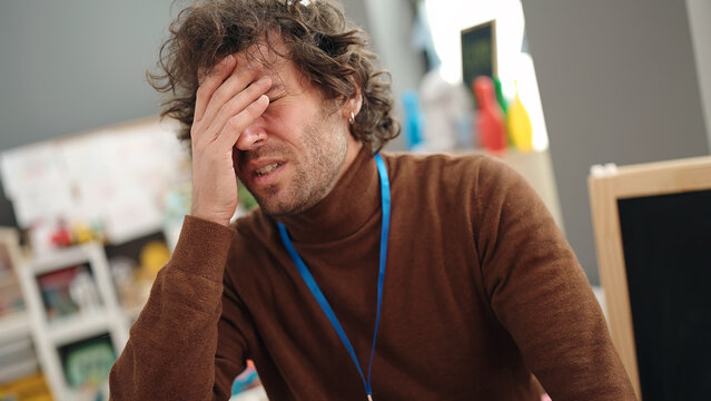 Young Hispanic Man Preschool Teacher Stressed At Kindergarten