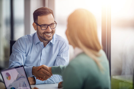 Two business people shaking hands while sitting at the working place