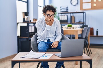 Hispanic man doing video call waving to laptop covering mouth with hand, shocked and afraid for...