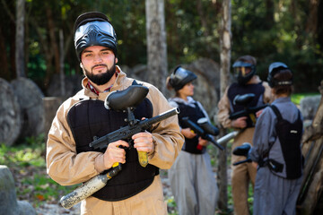Fototapeta premium Man and his paintball sport team in protective uniform at paintball shooting range