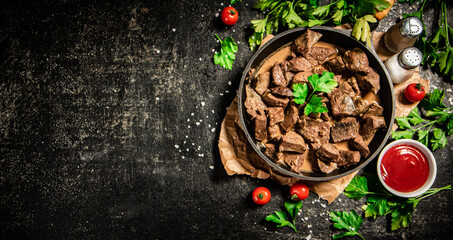 Liver cooked in a frying pan with cherry tomatoes and herbs. 