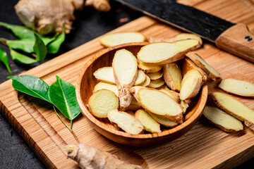 Chopped ginger on a cutting board with a knife. 