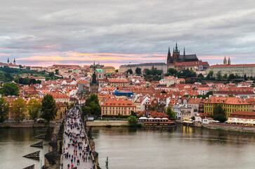 Fototapeta premium View at sunset from Old Town Bridge tower over the historical Charles bridge and Castle district with motion blur, Prague, Czech Republic