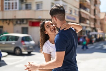 Young hispanic couple smiling confident hugging each other and dancing at street