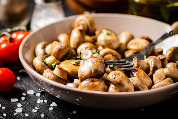 Fried mushrooms in a bowl with cherry tomatoes. 