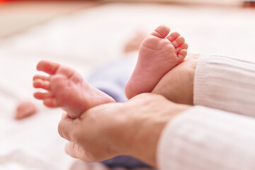 Mother and son lying on bed holding feet at bedroom