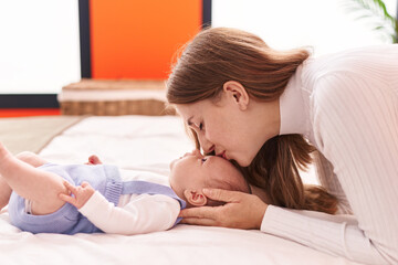 Mother and son lying on bed kissing baby at bedroom