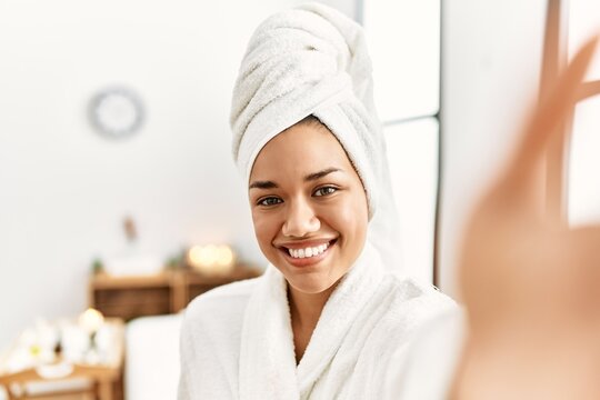 Young latin woman wearing bathrobe make selfie by the camera at beauty center