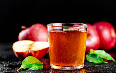 A full glass of apple juice with leaves.