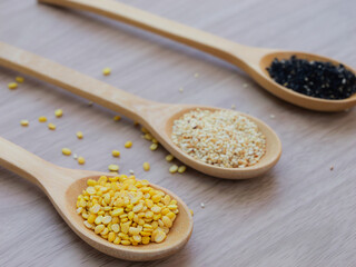 Yellow sesame, white sesame, and black sesame seed on wooden spoon, concept of healthy food.