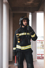 A young, uniformed firefighter speaking on the radio station to communicate with a colleague inside...