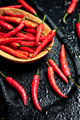 Pods of hot chili peppers on a cutting board.