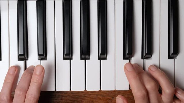 Close up view on the hands of a beginner pianist playing the piano. The pianist performs playing a piano. Hands close up. 4k resolution music video.