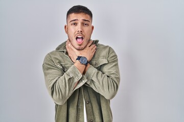 Fototapeta premium Young hispanic man standing over isolated background shouting suffocate because painful strangle. health problem. asphyxiate and suicide concept.
