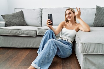 Young blonde woman smiling confident making selfie by the smartphone at home