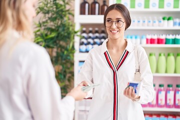 Young beautiful hispanic woman customer paying to pharmacist for pills at street