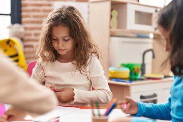 Two kids preschool students sitting on table drawing on paper at kindergarten