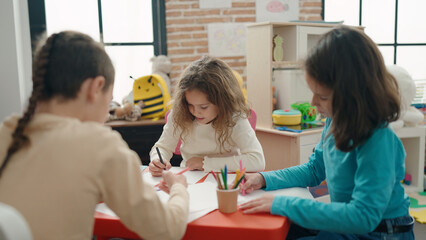 Group of kids preschool students sitting on table drawing on paper at kindergarten